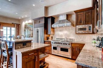 A modern kitchen with stainless steel appliances, dark wood cabinetry, and granite countertops in Village Walk 55.