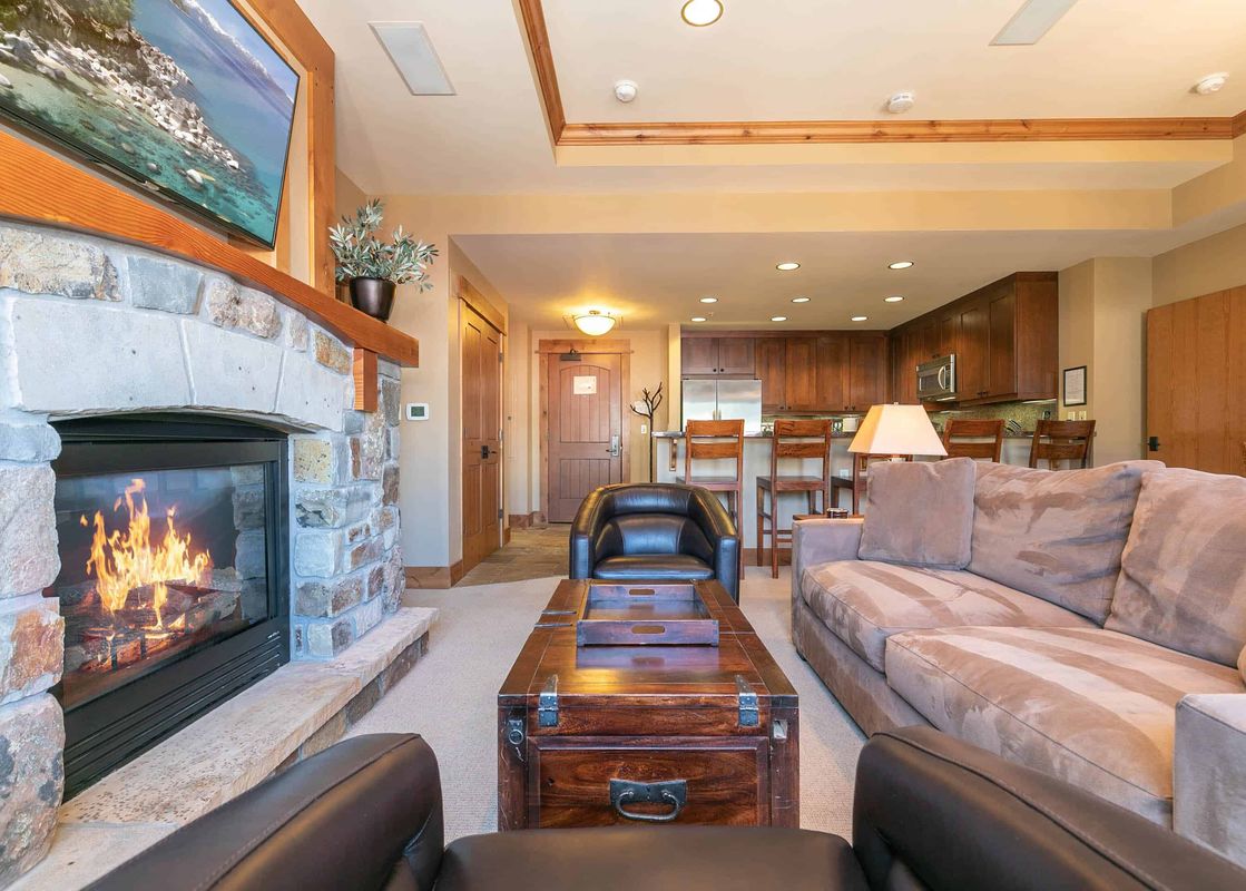 A living room with a fireplace, two leather armchairs, and a couch.
