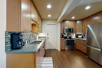 A modern kitchen with stainless steel appliances, light wood cabinets and a gray countertop.