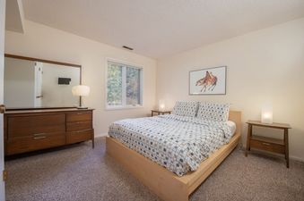A cozy and bright bedroom in Whiteridge B1 with a queen bed, wooden dresser, and bedside tables.