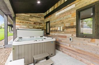 The hot tub on the patio at Dakota Haven features a rustic wooden wall and offers a relaxing outdoor retreat.