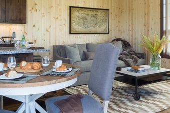 An inviting open-concept living area with a dining table set for breakfast, an adjacent lounge with a sofa, and a modern kitchen, all bathed in natural light.