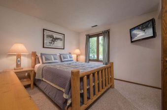 Cozy bedroom at Whiteridge B5 with a log-framed bed, rustic decor, and a wall-mounted TV.