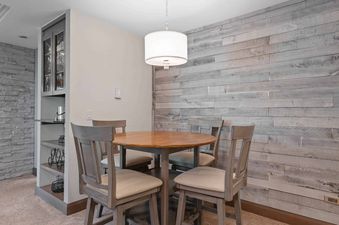 A cozy dining nook with a round wooden table, four chairs, and a pendant light, complemented by a rustic wood plank accent wall.