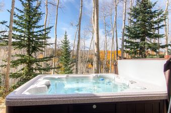 A hot tub overlooking a vibrant autumn forest and distant mountains.