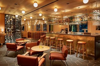 A luxurious and well-stocked bar area with golden accents, comfortable seating, and an extensive wine collection.