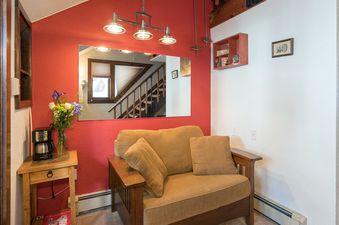 A cozy seating area in Manitou Lodge 11 features a comfortable couch, accented by a mirror reflecting the staircase.