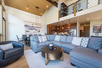 The spacious great room features a large sectional sofa, a coffee table, and an open-concept layout leading to the dining area and kitchen.