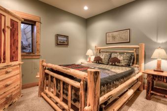 A cozy bedroom at Lone View Lodge features a rustic wooden log bed with nature-themed bedding, a wooden armoire, and soft lighting.