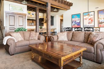 The living area of Silver Star 1305 features comfortable brown sofas, a large wooden coffee table, and an adjacent staircase leading to an upper level, with a kitchen and dining area visible in the background.