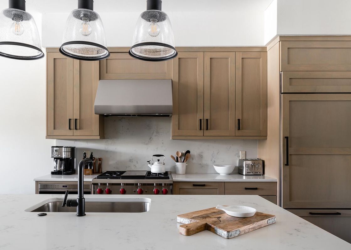 The kitchen in Moonlight Basin 10 Wildwood features stainless steel appliances, light-colored cabinets, and a breakfast bar with a view of the living area.