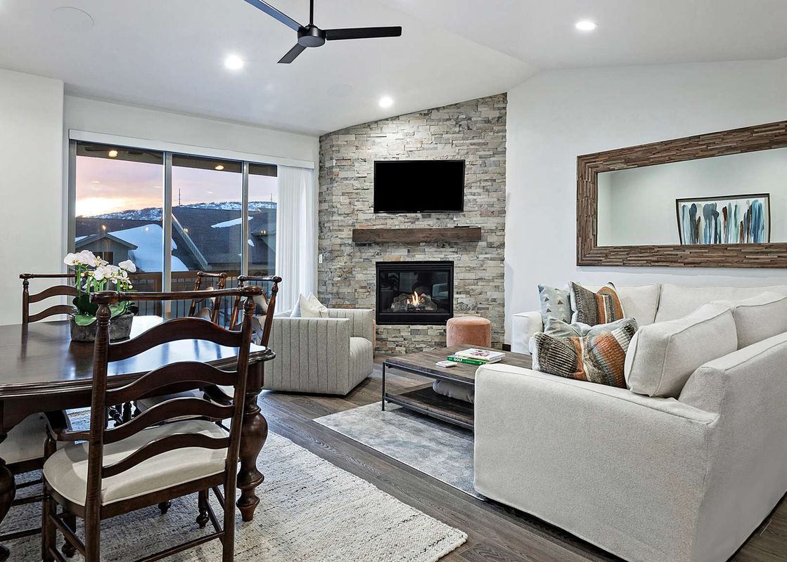 A spacious living room and dining area with a stone fireplace, a large wooden dining table with chairs, and comfortable sofas.