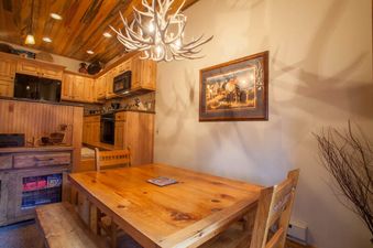 Dining table and chairs under an antler chandelier in Kutuk 112, with the kitchen in the background.