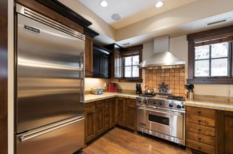 A modern kitchen at Silver Star 902 featuring stainless steel Viking appliances, dark wood cabinetry, granite countertops, and a tiled backsplash.