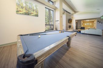 A pool table with billiard balls and cues in a spacious lounge area.