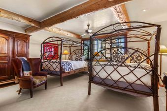 A bedroom with two canopy beds and a leather armchair.