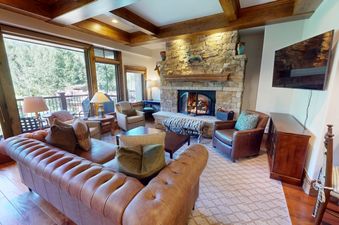 Cozy living room in the Ski Vista Penthouse with a stone fireplace and balcony view.