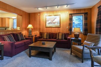 Living room of Windriver 1 with wood paneling and burgundy sofas.
