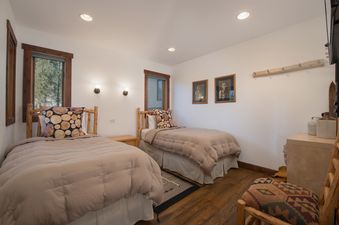 A cozy bedroom in Nez Perce D2 with two twin beds, rustic wooden furniture, and framed artworks on the wall.