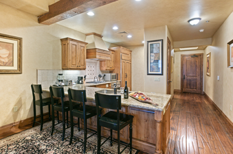 The kitchen in Grand Lodge Studio 204 features wooden cabinets, a granite countertop, and bar stools.