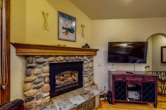 A cozy stone fireplace and flat-screen TV in the living area of Leeward 2688.
