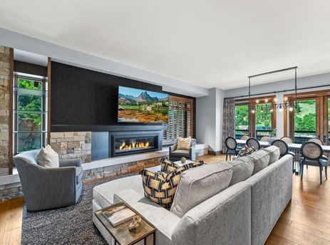 A living room with a fireplace, a large sectional couch, and a flat-screen television.