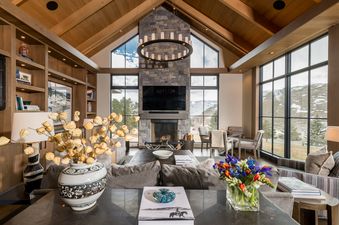 A living room with a fireplace and a large window offering a scenic view of a snowy mountain landscape.
