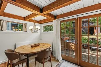 A cozy dining nook at Town Charm with a wooden table, leather chairs, and large glass doors leading to a deck.