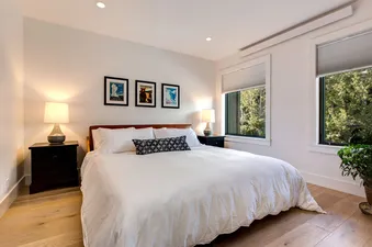 A white bedroom with a king-sized bed, a dresser and two lamps.
