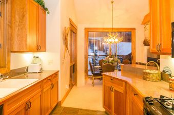 The kitchen in Terraces 602 features wood cabinets, stainless steel appliances, and a window with a view of the snowy mountains.