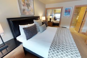 A modern and elegant bedroom in the Manor Vail Lodge Platinum 3 Bedroom Condo featuring a plush king-sized bed with decorative throw pillows.