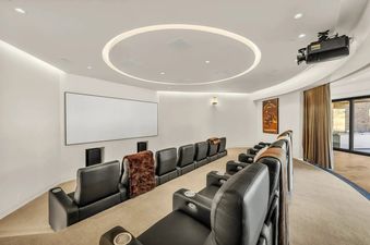A home cinema at The Foundry featuring tiered rows of black leather recliners facing a large white projection screen, with ambient lighting and a projector mounted on the ceiling.
