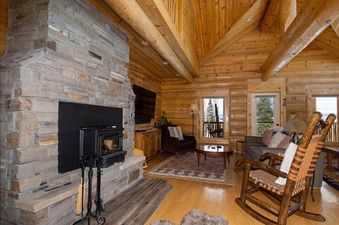 The living area of Miles Behind features a cozy stone fireplace, plush seating, and warm wooden interiors, creating a welcoming and comfortable atmosphere.