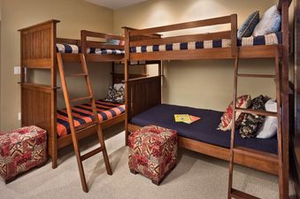 The bunk room at Sage Creek One Steamboat Place 105 features two wooden bunk beds with colorful bedding and decorative throw pillows, offering comfortable and inviting accommodations.