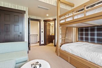 The bunk room at Flagstaff 507 features a wooden bunk bed with white bedding, a light blue sofa, and tree-patterned wallpaper.