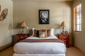 A bedroom at Moonlight Basin 2 Mountain Home with a plush king-sized bed, two side tables, and a large picture frame above the headboard.