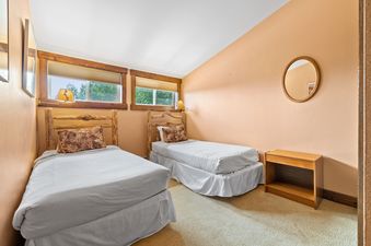 A cozy twin bedroom at Snowridge 6 with log-style bed frames and warm peach walls.