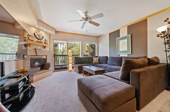 The living area at St James Place 325 features a comfortable sectional sofa, a fireplace, and a large TV, creating a perfect space for relaxation.