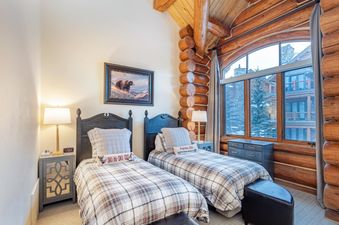 A cozy bedroom featuring two twin beds with a rustic, log-cabin aesthetic.