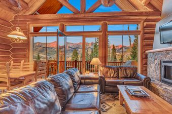 Spacious living area with a large leather sofa, a fireplace, and an amazing view of the mountains.