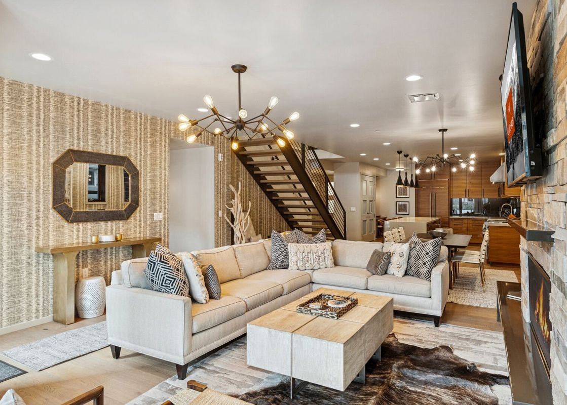 An expansive open-concept living room, dining area, and kitchen at Main Street Modern, featuring modern furnishings and a stylish sputnik chandelier.
