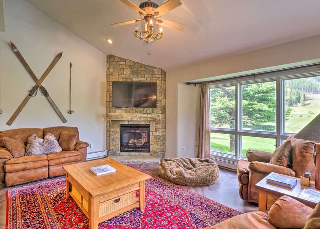 Cozy living room in Copper Mountain Home with Hot Tub featuring leather sofas, a stone fireplace, and scenic window views.
