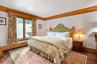 A cozy bedroom with a green bed, floral curtains, and a patterned rug.