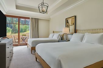 The Montage Deer Valley Two Bedroom Residence Vista View bedroom features two queen beds, a flat-screen TV, and a balcony with outdoor seating and mountain views.