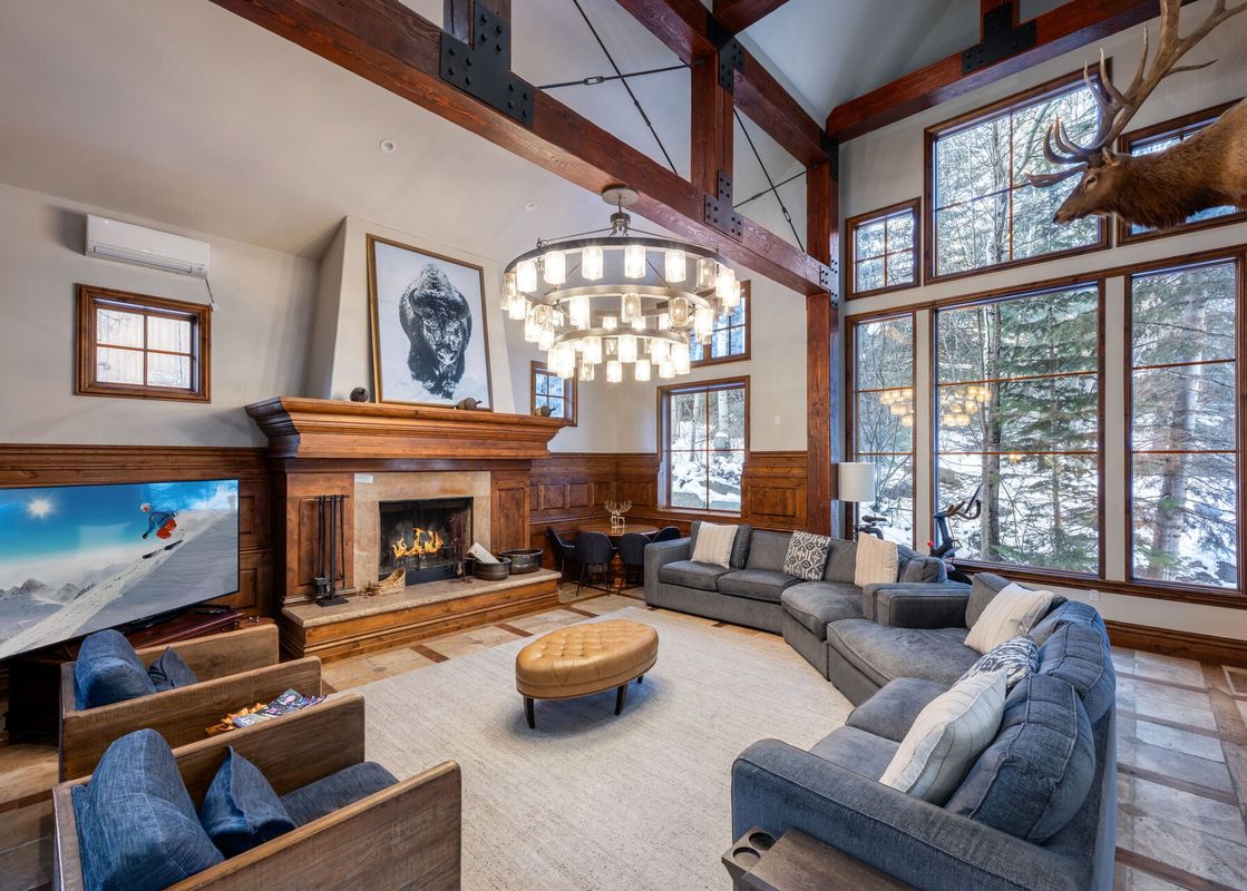 A rustic and elegant living room at Canyons Red Pine Chalet 91 with a fireplace and large windows.