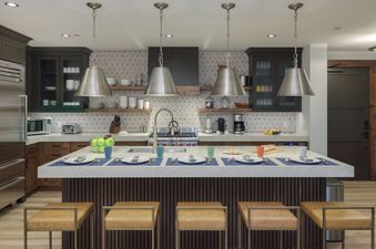 A modern kitchen with stainless steel appliances, a breakfast bar with stools, and a view of a dining area.