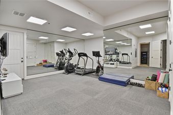 Well-equipped home gym at Snow Dance at The Colony with cardiovascular machines and wall-to-wall mirrors.