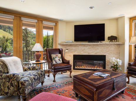 Cozy living room with a fireplace, leather armchairs, and scenic pine-tree views at 411 Beaver Creek Lodge.