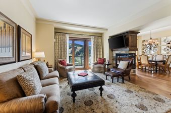 The living area of the St Regis Madison Residence, featuring comfortable seating, a fireplace, and large windows with mountain views.