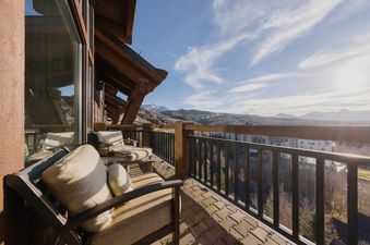A private balcony at Lynx Lookout at See Forever offers stunning mountain and valley views, complete with comfortable outdoor seating and a textured floor.